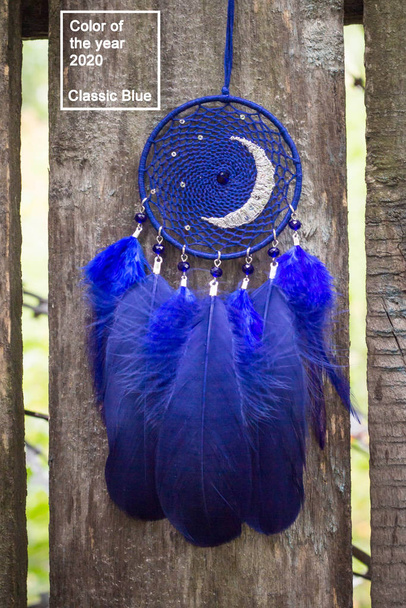 Handgemaakte droomvanger met veren draden en kraaltjes touw in klassieke blauwe trendy kleur van het jaar 2020. - Foto, afbeelding