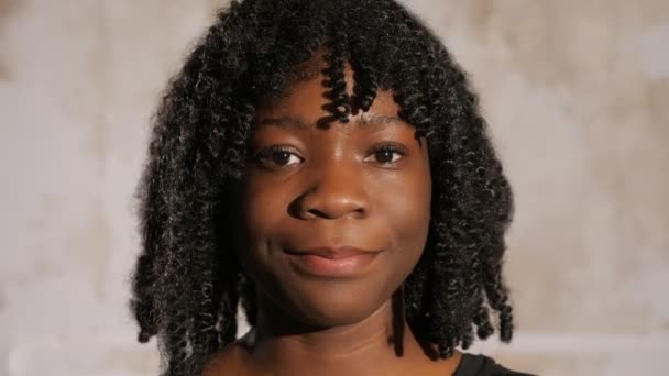 Афроамериканська дівчинка з кучерявим волоссям дивиться вперед і посміхається - Кадри, відео