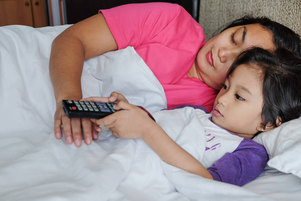 asiatico bambino su letto utilizzando telecomando per guardare la televisione
 - Foto, immagini