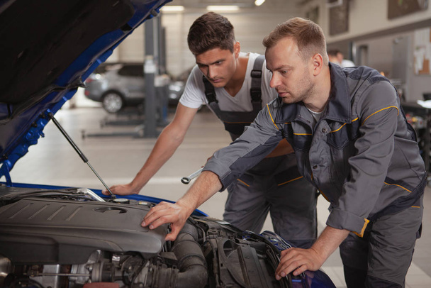 Dois mecânicos masculinos a trabalhar na garagem
 - Foto, Imagem
