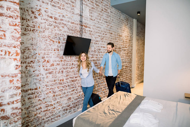 Young Couple at Hotel Room. Vacation starts. Young couple entering in their holiday rental apartment or modern loft hotel room with brick wall - Photo, Image