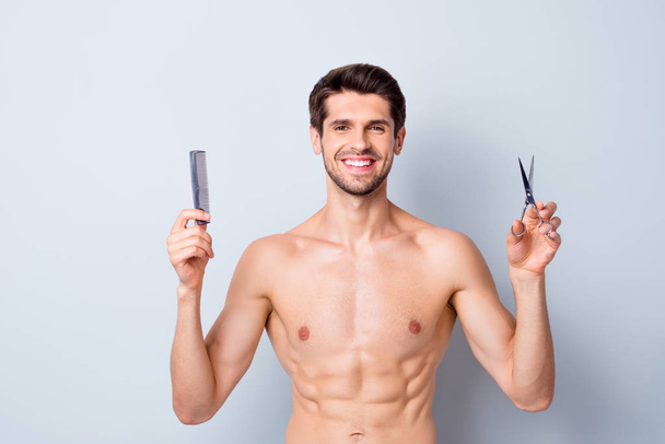 Portrait of his he nice attractive cheerful cheery guy holding in hands hairdress tools scissors and comb hairdresser domestic salon isolated on light white grey color pastel background - Фото, изображение