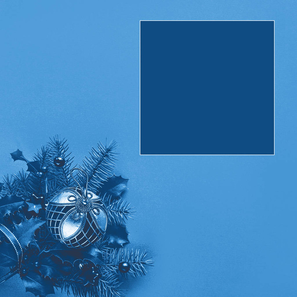 Ünnepi monokróm kék színű karácsonyi háttér, négyzet összetétel másolási hely színes swatch. Díszes csecsebecse, csíkos cukornád Holly-n és fenyő gallyak a sarokban. - Fotó, kép