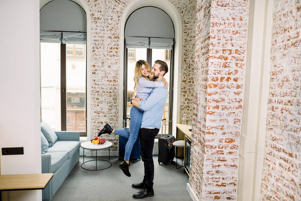 Attractive happy young couple in love having fun and hugging in hotel room with brick walls. - Foto, immagini