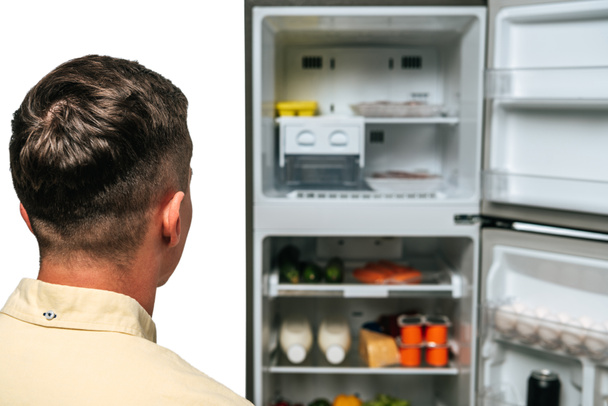 guy looking at open fridge with food isolated on white - Photo, Image