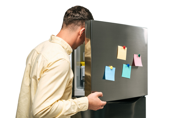 guy looking in open fridge with sticky notes isolated on white - Photo, image