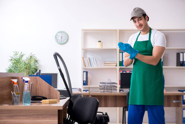 Fiatal jóképű vállalkozó takarítja az irodát - Fotó, kép