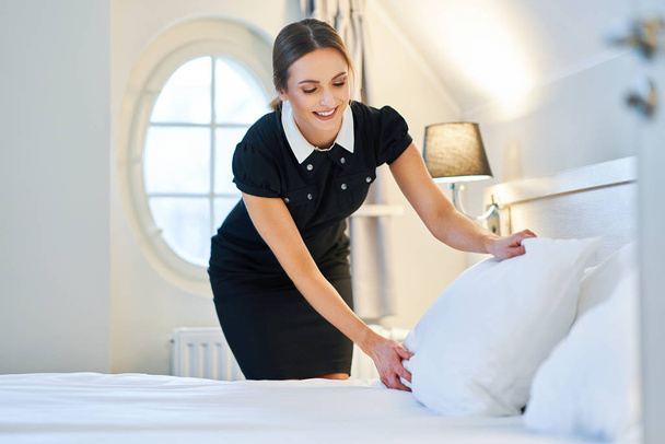 Maid making bed in hotel room - Photo, Image