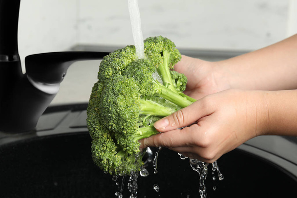 Woman washing fresh green broccoli in kitchen sink, closeup - Foto, Imagem