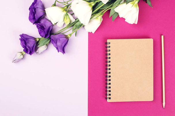 Valentinstag-Karte mit Kopierplatz. Zarte Eustonia-Blüten auf rosa Hintergrund. Blumen und leeres Notizbuch auf farbigem Papier Hintergrund - Foto, Bild