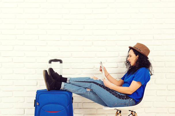 Young woman chooses a place to travel using map sitting in office travel agency. Adventure, vacation and holiday concept - Photo, Image