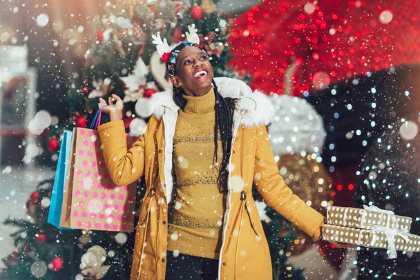 African girl shopping gifts in mall on christmas sale. New year  - 写真・画像