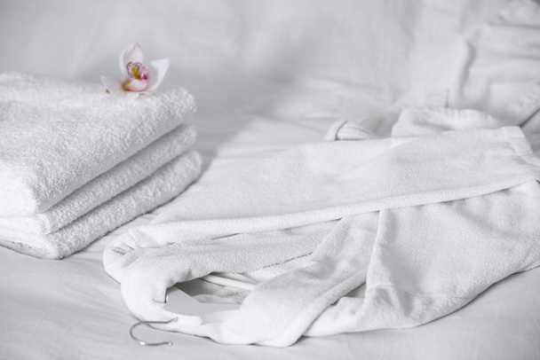 Clean soft bathrobe and towels on bed - 写真・画像