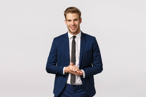 Handsome and confident, smart male entrepreneur in classic suit, rubbing palms and smiling pleased, anticipate make big money, good deal, relish something good, standing white background - Фото, зображення