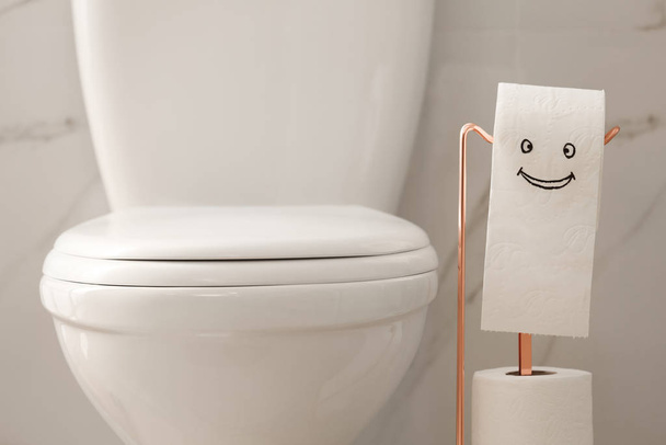 Modern toilet bowl and paper with funny face in bathroom - Foto, Imagem