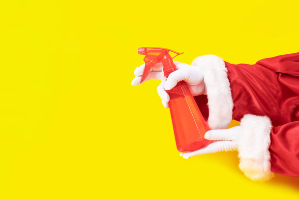 Santa Claus glove hand yellow background spray dispenser one red suit copy space - Foto, Imagem