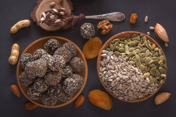 Morsi naturali sani di energia cruda, pasta di cioccolato e mix di frutta secca con noci su un tavolo scuro. Vista dall'alto
 - Foto, immagini
