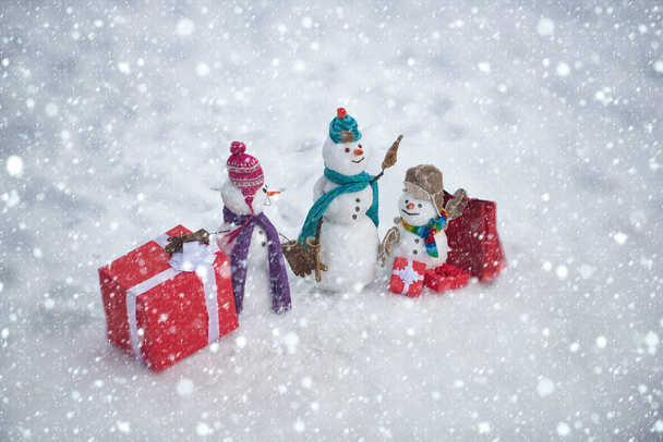 Handmade snowman in the snow outdoor. Greeting snowman. Winter snowman family. Mother snow-woman, father snow-man and kid on Christmas background. - Photo, Image