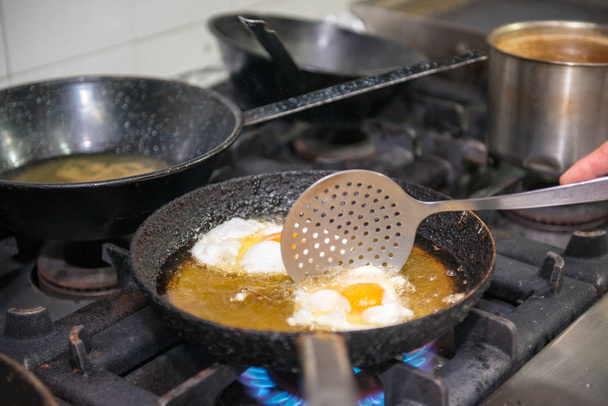 Préparation de deux œufs frits dans une poêle remplie d'huile
. - Photo, image