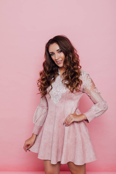 Portrait of a beautiful fashionable woman with hair curls in a pink dress - Foto, afbeelding