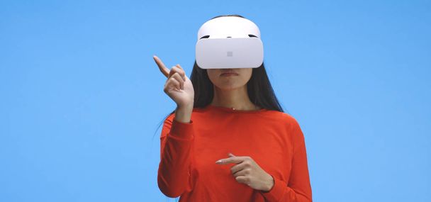Młoda kobieta nosi zestaw słuchawkowy VR i wykonuje gesty dłoni - Zdjęcie, obraz