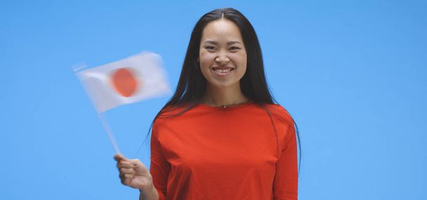 Молода жінка махає японським прапором. - Фото, зображення