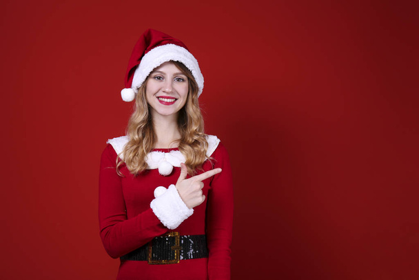 Smiling woman wearing celebratory outfit on red wall background. - Φωτογραφία, εικόνα