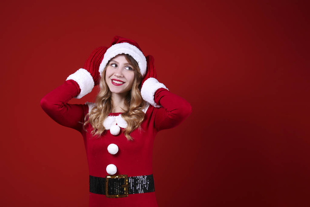 Smiling woman wearing celebratory outfit on red wall background. - Фото, изображение