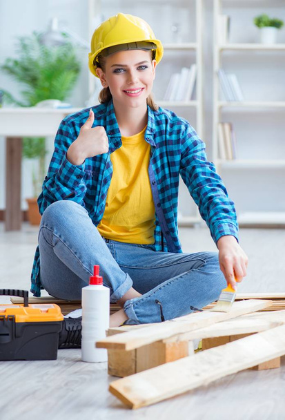 Female repairman carpenter cutting joining wooden planks doing r - 写真・画像