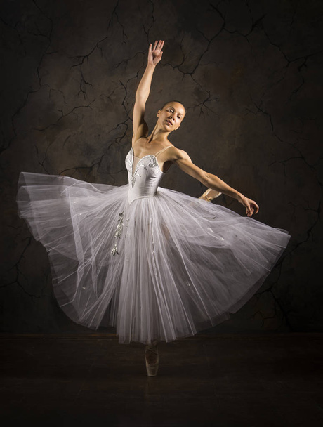 Slender girl in a white corset tutu dancing ballet. Studio shooting on a dark background, isolated images. - Foto, Imagem