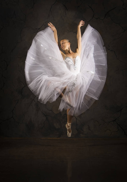 Slender girl in a white corset tutu dancing ballet. Studio shooting on a dark background, isolated images. - Фото, изображение