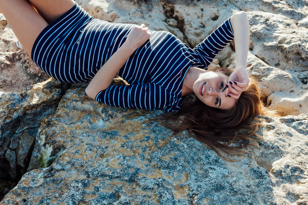 дівчина лежить на спині на кам'яному пляжі
 - Фото, зображення