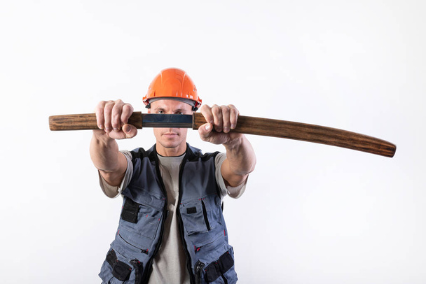 Le constructeur tire un katana de sa gaine, devant lui. Réparateur portant un casque et des vêtements de travail
. - Photo, image