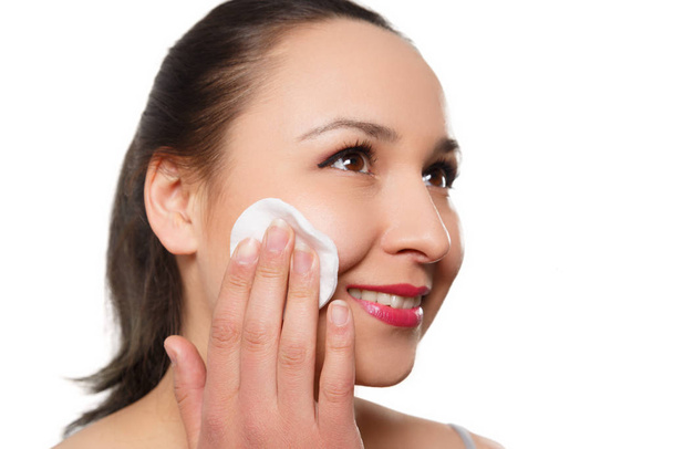 una giovane donna si pulisce il viso con un batuffolo di cotone. isolato su sfondo bianco
 - Foto, immagini