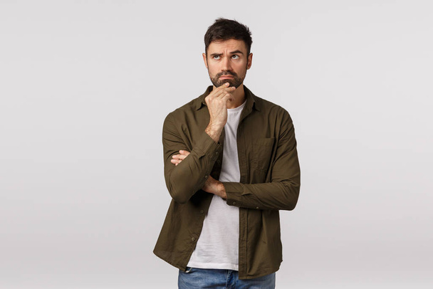 Man thinking, taking serious decision, making hard choice, Serious-looking bossy caucasian bearded male in coat, touching chin, look focused upper left corner, making plan, search solution - Foto, imagen