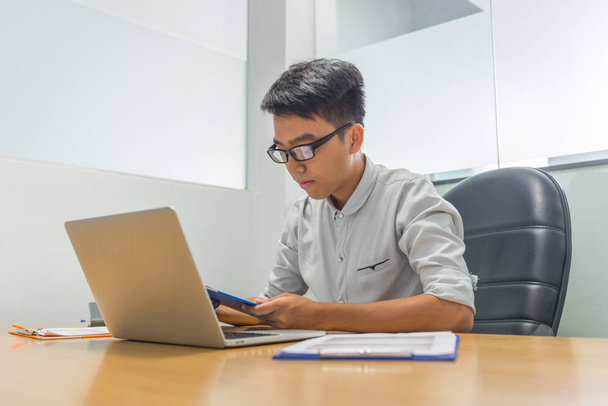 Nuori aasialainen liikemies lukeminen raportti toimistossa
 - Valokuva, kuva