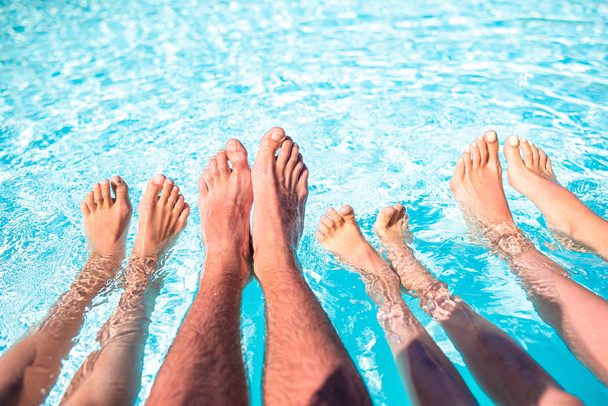Close up of four peoples legs by pool side - Фото, изображение