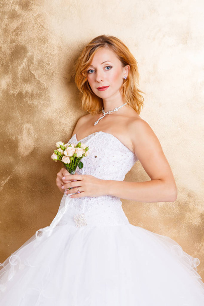Beautiful bride in white bridal dress on gold backdrop - 写真・画像