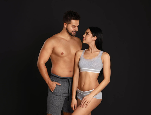 Young couple in grey sportive underwear on black background - Фото, зображення