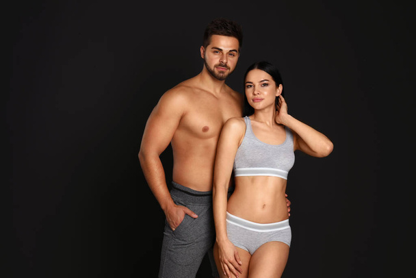Young couple in grey sportive underwear on black background - Φωτογραφία, εικόνα