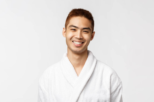 Sonriente joven asiático en blanco albornoz Retrato estudio aislado
. - Foto, imagen