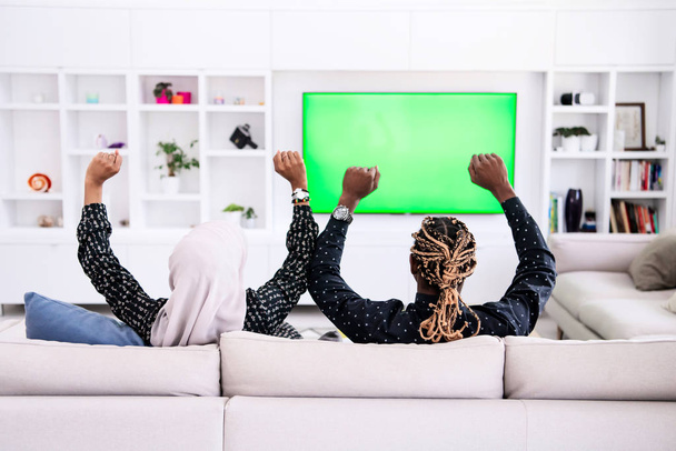 African Couple Sitting On Sofa Watching TV Together - Foto, immagini