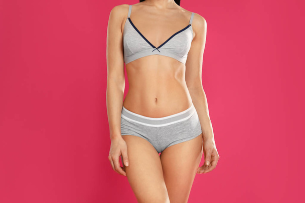 Young woman in grey sportive underwear on pink background, closeup - Photo, image