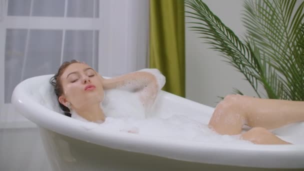 Bella donna rilassante nel bagno di bolle che giace nella vasca da bagno. Cura della bellezza, attività ricreative e concetto sanitario
 - Filmati, video