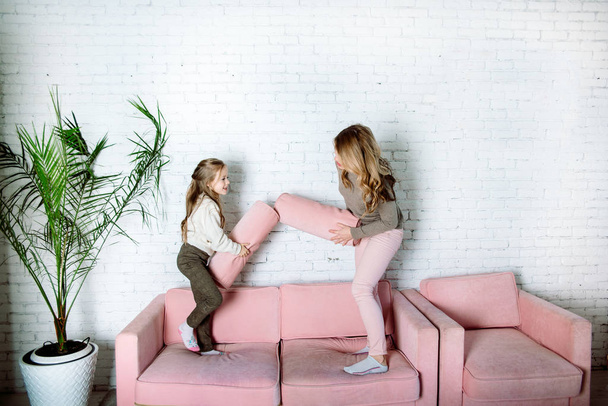 Parental love, upbringing and care.Happy mommy and kid daughter holding hands jumping on sofa together, baby sitter or mother playing having fun with cute kid girl at home - Foto, Imagen