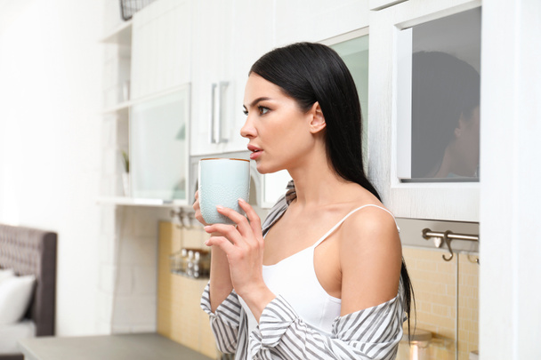 Красива молода жінка в білій білизні п'є каву вдома
 - Фото, зображення