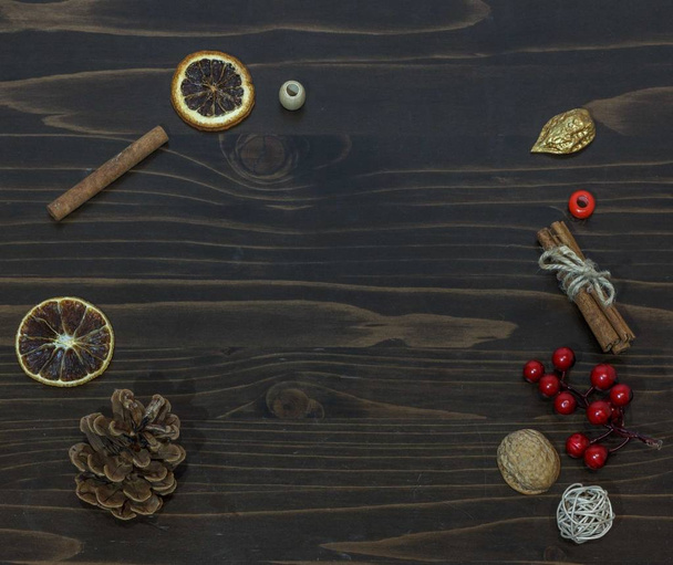 Christmas composition with orange, spices, cone on dark wooden background, empty center, top view - Photo, Image