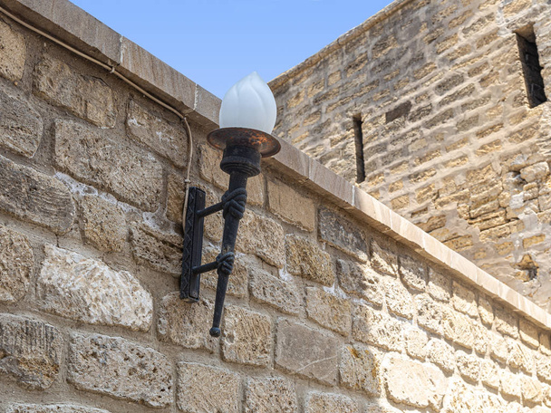 Вулична лампа у вигляді факела на стіні фортеці
 - Фото, зображення