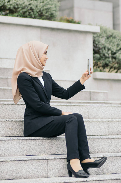 Portrait of young Businesswoman in black suit using a mobile phone for a video call with partners or selfie - Fotó, kép