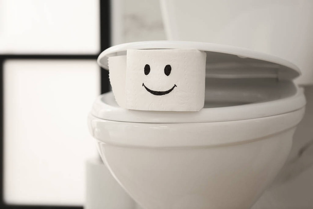 Roll of paper with funny face on toilet bowl in bathroom - Foto, Imagem